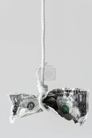Photo for Crumpled one dollar bill hanging on a tightly knotted white rope. Concept of money fraud, debt or credit payments. - Royalty Free Image