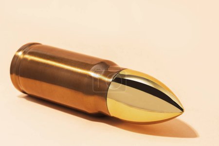 Photo for One big shiny bullet against beige background - Royalty Free Image