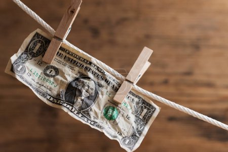 Photo for One dollar bill is drying on a white rope, held by laundry pins. Councept of money saving or money laundering. - Royalty Free Image