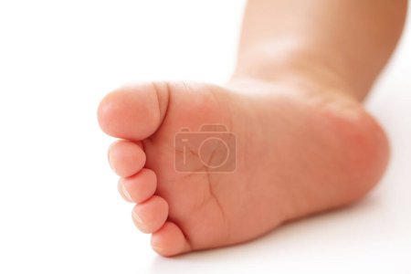 Téléchargez les photos : Gros plan du pied d'un petit enfant avec une peau lisse et douce sur fond blanc. - en image libre de droit