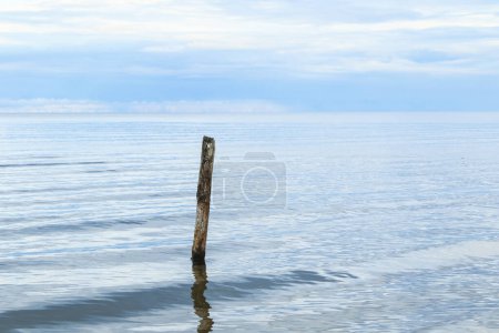 Photo for A beautiful shot of a a calm sea scenery with broken pier pole sticking out of water on horizon background. - Royalty Free Image