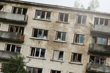 Foto de Exterior de un edificio de apartamentos abandonado con ventanas rotas en un pueblo fantasma europeo desolado. - Imagen libre de derechos