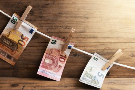 Téléchargez les photos : Les billets en euros de différentes valeurs sont séchés sur une corde blanche, tenue par des pinces à linge. Compte d'épargne ou de blanchiment d'argent. - en image libre de droit