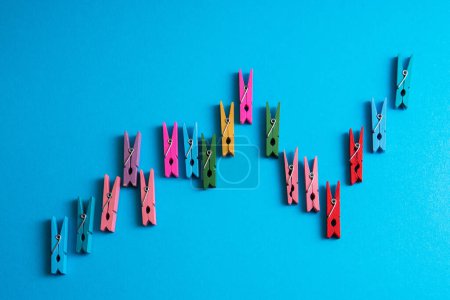 Photo for Closeup shot of a financial graph made of colorful wooden clothespins on blue background. - Royalty Free Image