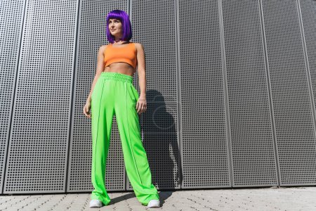 Téléchargez les photos : Portrait de jeune femme portant des vêtements de sport colorés posant dans la rue pendant la journée d'été - en image libre de droit