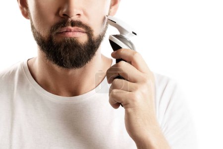 Photo for Bearded man is using electric trimmer on white background - Royalty Free Image