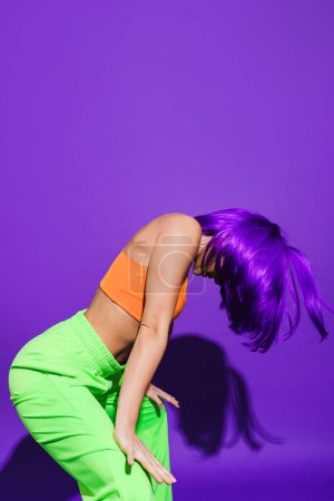 Photo for Carefree active woman dancer wearing colorful sportswear having fun against purple background - Royalty Free Image