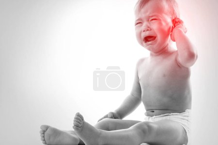 Photo for Closeup of little crying baby suffering from a ear pain - Royalty Free Image