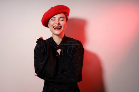 Téléchargez les photos : Portrait de mode de jeune belle femme riante portant un béret rouge - en image libre de droit
