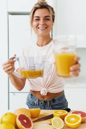 Photo for Young cheerful woman with big glass of fresh orange juice at home - Royalty Free Image