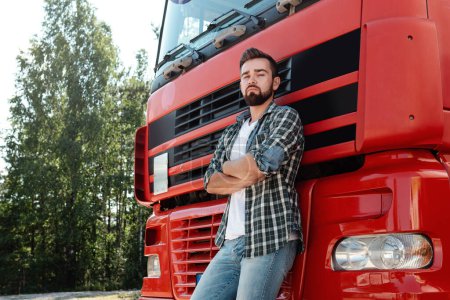 Téléchargez les photos : Conducteur de camion masculin confiant debout à côté de son camion de fret rouge - en image libre de droit