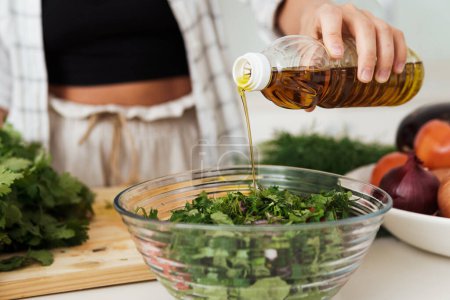 Photo for Closeup of female hand adding extra virgin olive oil to vegetarian salad - Royalty Free Image