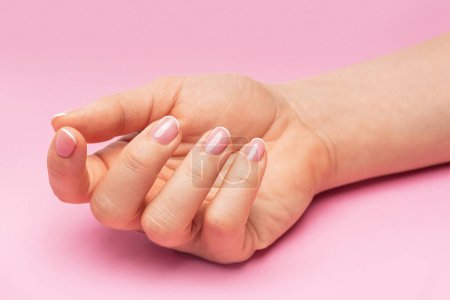 Foto de Primer plano de la mano femenina con piel suave y hermosa manicura francesa sobre fondo rosa - Imagen libre de derechos