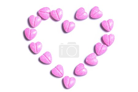 Photo for Closeup shot of a heart symbol made of pink heart shaped pills on white background. - Royalty Free Image