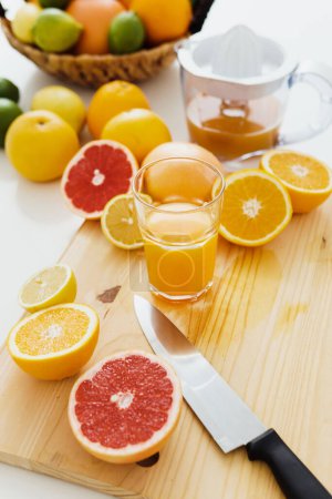 Photo for Closeup of sliced citrus fruits and glass of fresh orange juice on the cutting board - Royalty Free Image