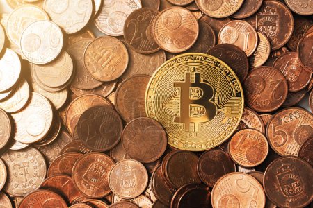 Téléchargez les photos : Gros plan d'un bitcoin doré brillant sur un tas de pièces en euros en cuivre. - en image libre de droit