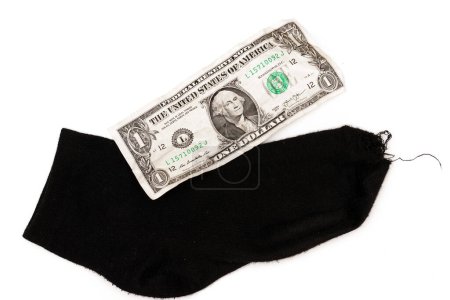 Foto de Primer plano de un billete de un dólar y un calcetín negro sobre fondo blanco. Concepto de pobreza y crisis financiera. - Imagen libre de derechos