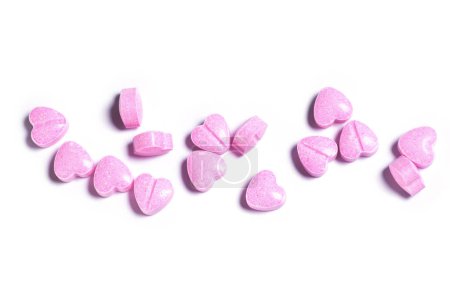 Foto de Primer plano de varias píldoras en forma de corazón rosa sobre fondo blanco. - Imagen libre de derechos