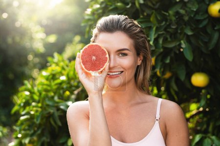 Photo for Outdoor portrait of beautiful woman with smooth skin with a grapefruit in her hands - Royalty Free Image