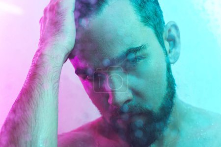 Photo for Portrait of handsome young man captured through wet glass in colorful neon light - Royalty Free Image