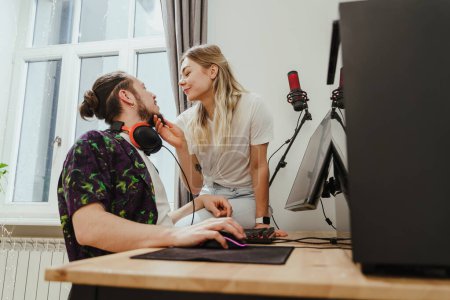 Photo for Young sensual couple relaxing and showing love while playing video games on a personal computer - Royalty Free Image
