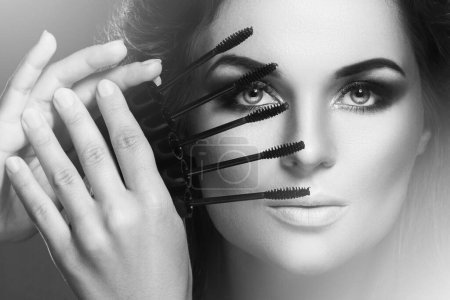 Photo for Stunning woman with beautiful make-up is holding lot of  mascara wands near her face - Royalty Free Image