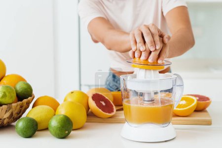 Photo for Closeup of female hands and citrus juicer during fresh orange juice preparation - Royalty Free Image