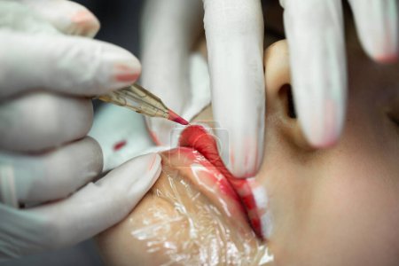 Foto de Mujer joven durante el procedimiento de maquillaje permanente profesional - rubor labial - Imagen libre de derechos