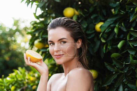 Téléchargez les photos : Portrait extérieur de belle femme à la peau lisse avec un fruit de citron dans ses mains - en image libre de droit