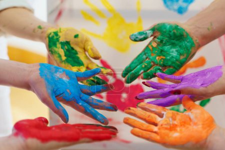 Foto de Primer plano de las palmas femeninas en colores coloridos de pintura arco iris creando obras de arte modernas para apoyar a la comunidad LGBT - Imagen libre de derechos