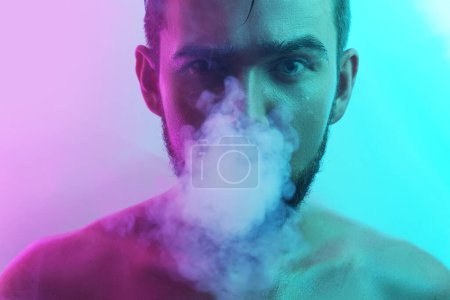 Foto de Retrato de un joven guapo con piel mojada en humo de luz ultravioleta - Imagen libre de derechos