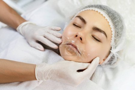 Foto de Artista de maquillaje permanente profesional que aplica anestésico en los labios del cliente antes del procedimiento de rubor labial - Imagen libre de derechos