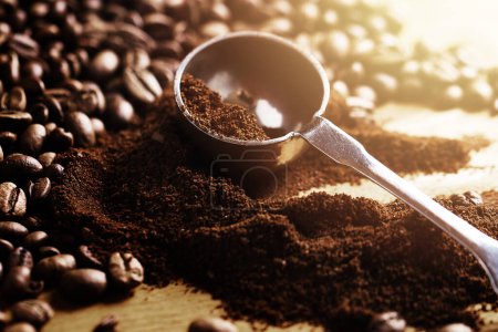 Photo for Closeup of steel spoon, grounded coffee and beans  on wooden table - Royalty Free Image