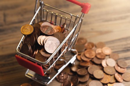 Photo for Closeup shot of a tiny shopping cart filled with shiny small value copper euro coins. - Royalty Free Image