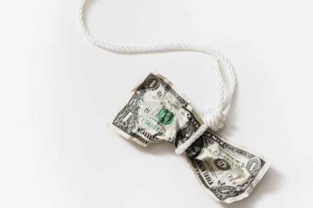 Téléchargez les photos : Corde blanche enchevêtrée autour d'un billet d'un dollar froissé. Notion de fraude monétaire, de paiement de dettes ou de crédits. - en image libre de droit
