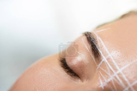 Foto de Primer plano de la frente femenina durante el procedimiento profesional de mapeo de cejas - Imagen libre de derechos