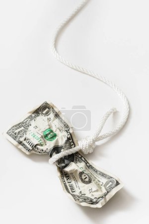 Photo for White rope tangled around a crumpled one dollar bill. Concept of money fraud, debt or credit payments. - Royalty Free Image
