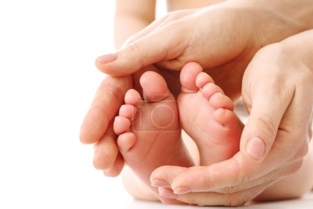 Téléchargez les photos : Gros plan d'une mère massant doucement les pieds et les semelles de son petit enfant sur fond blanc. - en image libre de droit