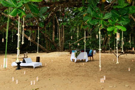 Téléchargez les photos : Table à manger aménagée pour un rendez-vous romantique sur une plage de sable, entourée de bougies. - en image libre de droit
