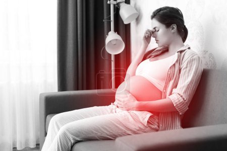 Téléchargez les photos : Jeune femme enceinte allongée sur le canapé à la maison avec un mal de tête douloureux - en image libre de droit