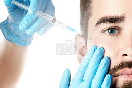 Téléchargez les photos : Jeune bel homme recevant une injection faciale pour le rajeunissement de la peau - en image libre de droit