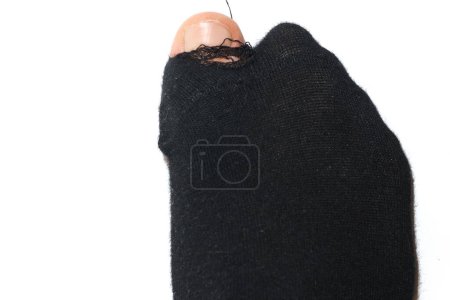Photo for Closeup shot of a black holey sock on a male foot with toe sticking out on white background. Concept of poverty and financial crisis. - Royalty Free Image