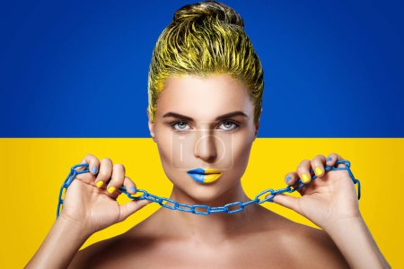 Foto de Mujer fuerte y confiada con lápiz labial azul amarillo y bandera de Ucrania en el fondo - Imagen libre de derechos