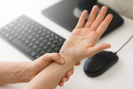 Closeup of female hands with a pain in the wrist because of carpal tunnel syndrome 