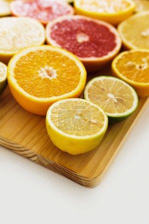 Photo for Different sliced citrus fruits such as grapefruit, orange, lemon and lime on cutting board against white background - Royalty Free Image