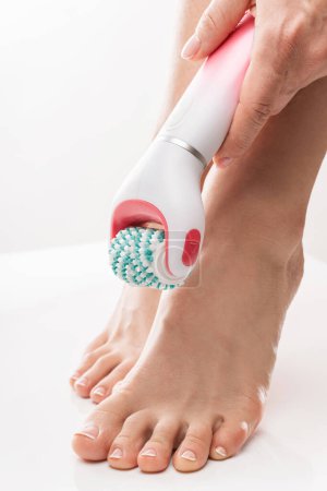Téléchargez les photos : Gros plan de pieds féminins et laveur de pieds électrique ou dispositif de massage sur fond blanc - en image libre de droit