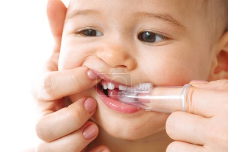 Téléchargez les photos : Gros plan d'une mère qui brosse doucement les dents de son petit enfant avec une brosse à dents - en image libre de droit