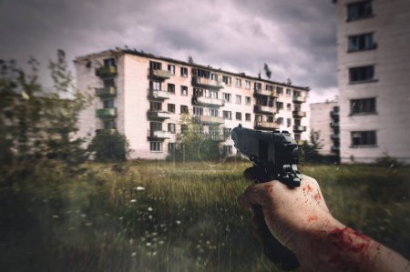 Foto de Vista en primera persona de la mano masculina real con pistola negra en la ciudad fantasma abandonada. Escena parece un videojuego FPS. - Imagen libre de derechos
