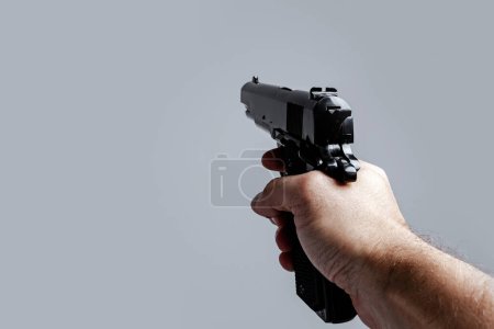 Foto de Vista en primera persona de la mano masculina con pistola negra aislada sobre fondo gris. - Imagen libre de derechos
