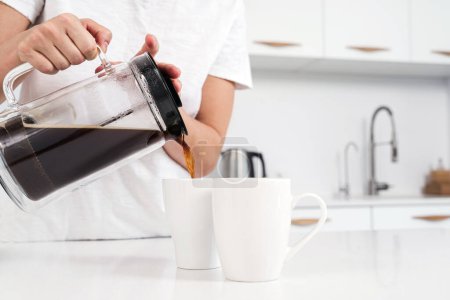 Photo for Closeup of French press and black coffee pouring into white mug. - Royalty Free Image